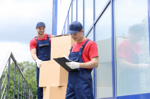 Professional movers carrying boxes in a Hounslow flat staircase